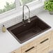 A Zurn Elkay mocha quartz drop-in sink in a brown countertop with a plant in front of it.