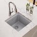A Zurn Elkay Quartz Classic greystone bar sink filled with ice and limes on a counter.