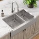 A Zurn Elkay stainless steel farmhouse sink with two compartments in a marble counter.