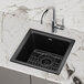 A Zurn Elkay black quartz bar sink with a black faucet and drain on a counter.
