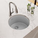 A Zurn Elkay Greystone Quartz bar sink filled with ice water and lime slices on a marble counter.
