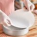 A person in gloves holding a Baker's Lane Quilon-coated round white paper.