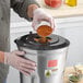 A person using an AvaMix heavy-duty blender to pour brown powder into a metal container.