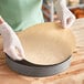 A person in gloves using a circular piece of Baker's Lane parchment paper.