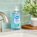 A bottle of Dial Spring Water liquid hand soap on a kitchen counter next to a plant.