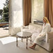 A woman in a white Telegraph Hill seersucker bath robe sitting on a couch.