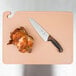 A knife and a chicken on a San Jamar brown cutting board.