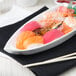 A white porcelain sushi boat on a table with sushi.