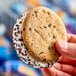 A hand holding a Blue Bunny Chips Galore frozen dessert sandwich.