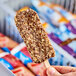A person's hand holding a Blue Bunny chocolate and peanut butter ice cream bar.