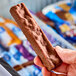 A person holding a SNICKERS Ice Cream Bar.