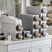 A ServSense stainless steel lid organizer on a counter with coffee cups in it.