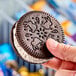 A hand holding a Blue Bunny Cookies 'n Cream frozen dessert sandwich.