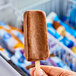 A hand holding a Blue Ribbon Fudge ice cream bar.