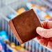 A close-up of a hand holding a Blue Bunny Big Alaska frozen dessert bar.