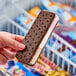 A person holding a Blue Bunny Neapolitan ice cream sandwich.