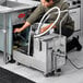 A man using a Fryclone portable fryer oil filter machine on a counter in a professional kitchen.