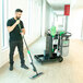 A man using an Unger Spot Cleaning Janitorial Cart System to clean a hospital hallway with a mop.