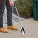 A man using a Lavex Trigger Grip reaching tool to pick up trash.