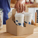 A man holding a Choice drink carrier with coffee cups inside.