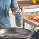 A woman spraying White Cap All-Purpose Food Release from a can onto a frying pan.