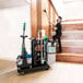 A man in a black shirt using an Unger Deep Cleaning Janitorial Cart to clean a staircase with a mop and broom.