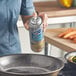 A woman spraying White Cap All-Purpose Food Release Spray on a frying pan.