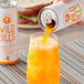 A hand pouring Wild Bill's Orange Cream Soda into a glass with a straw.