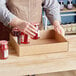 A person putting jam in a Kraft corrugated half tray.