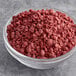 A bowl of Yum Crumbs Red Velvet crumb topping with red crumbs.