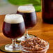 A bowl of Roses Dryden and Palmer brown rock candy on a table with a glass of dark liquid.