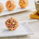 A round doughnut with pink and yellow Yum Crumbs on a table.