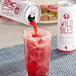 A hand pouring Wild Bill's Black Cherry Soda into a glass of ice.