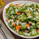 A plate of salad with spinach, carrots, and nuts.