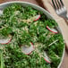 A bowl of kale salad with radish and cheese on a table.