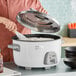 A person using a Galaxy commercial rice cooker to cook rice.