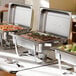 A Choice stainless steel chafing dish with food in it on a buffet table.