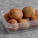 A plastic container with kiwis in it.