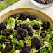A bowl of mixed greens with blackberries.