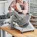 A person cutting meat on a Ecoline by Hobart manual meat slicer.