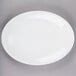 A Libbey Porcelana bright white oval platter with rolled edges on a gray surface.