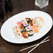 Libbey Porcelana oval coupe platter with sushi, shrimp, and chopsticks on a table.