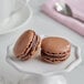 Two brown macarons on a white plate.