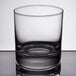 A Libbey rocks glass with a small amount of liquid on a table.