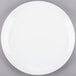 A Libbey Porcelana bright white round porcelain coupe plate on a gray surface.