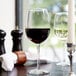 A Libbey Vina wine glass filled with red wine on a table.
