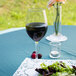 A Libbey tall wine glass filled with red wine on a table with a salad plate.