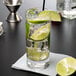 A Reserve by Libbey Modernist beverage glass of water with ice and lime slices and a lime wedge.