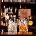 Two Libbey Carats rocks glasses with ice and amber liquid on a bar.