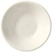 A Libbey Porcelana cream white porcelain fruit bowl with a rolled edge on a white surface.